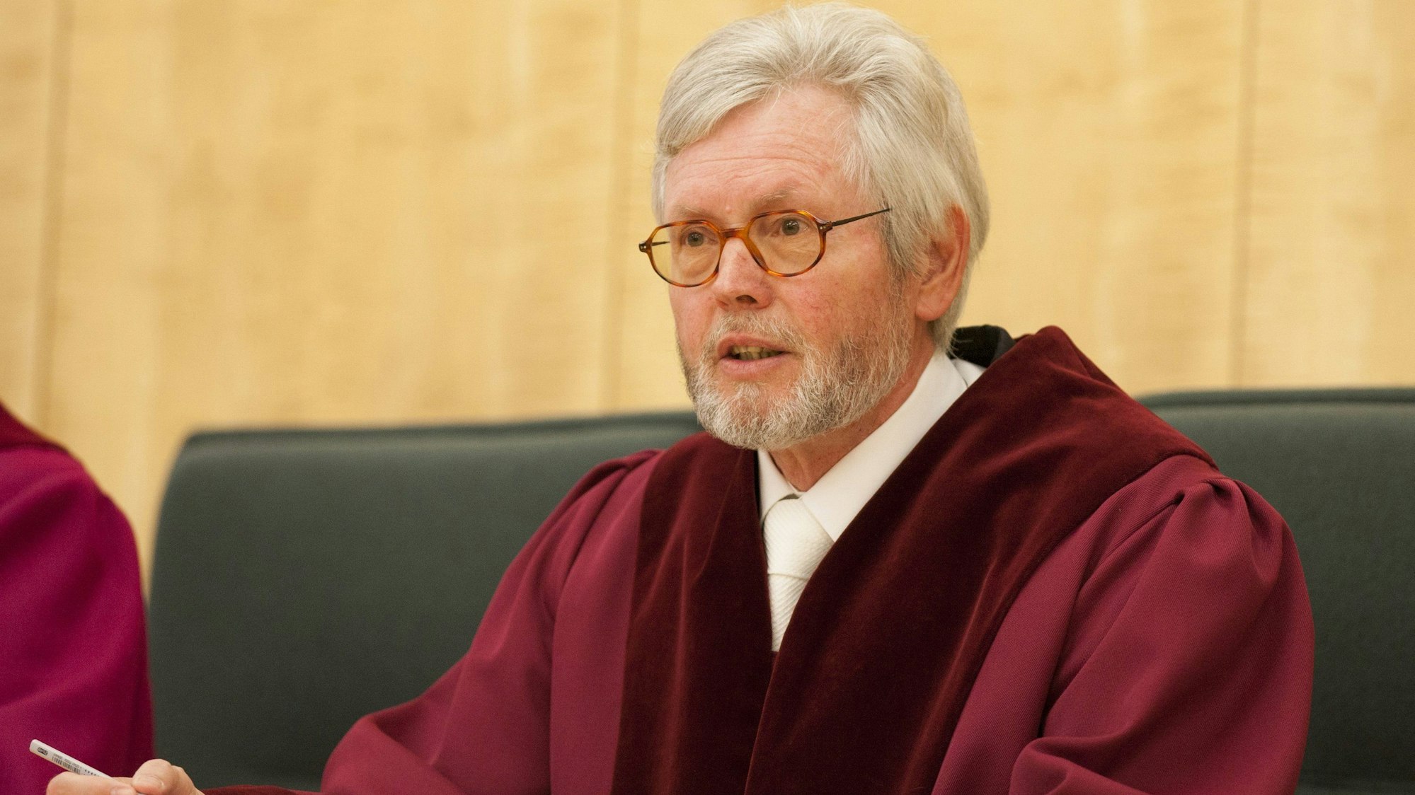 Der ehemalige Präsident des Verfassungsgerichtshofs, Michael Bertrams, schaut in die Ferne. Er trägt eine rote Richterrobe.