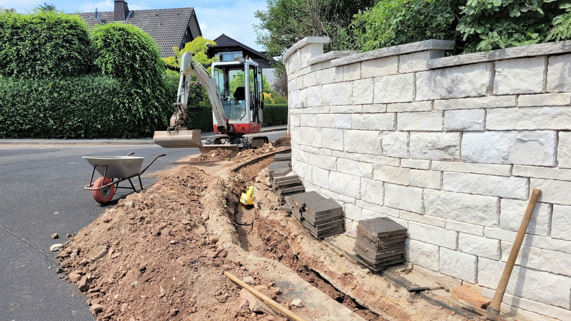 Das Foto zeigt einen Bagger und einen aufgerissenen Bürgersteig, in dem die neue Leitung verlegt wird