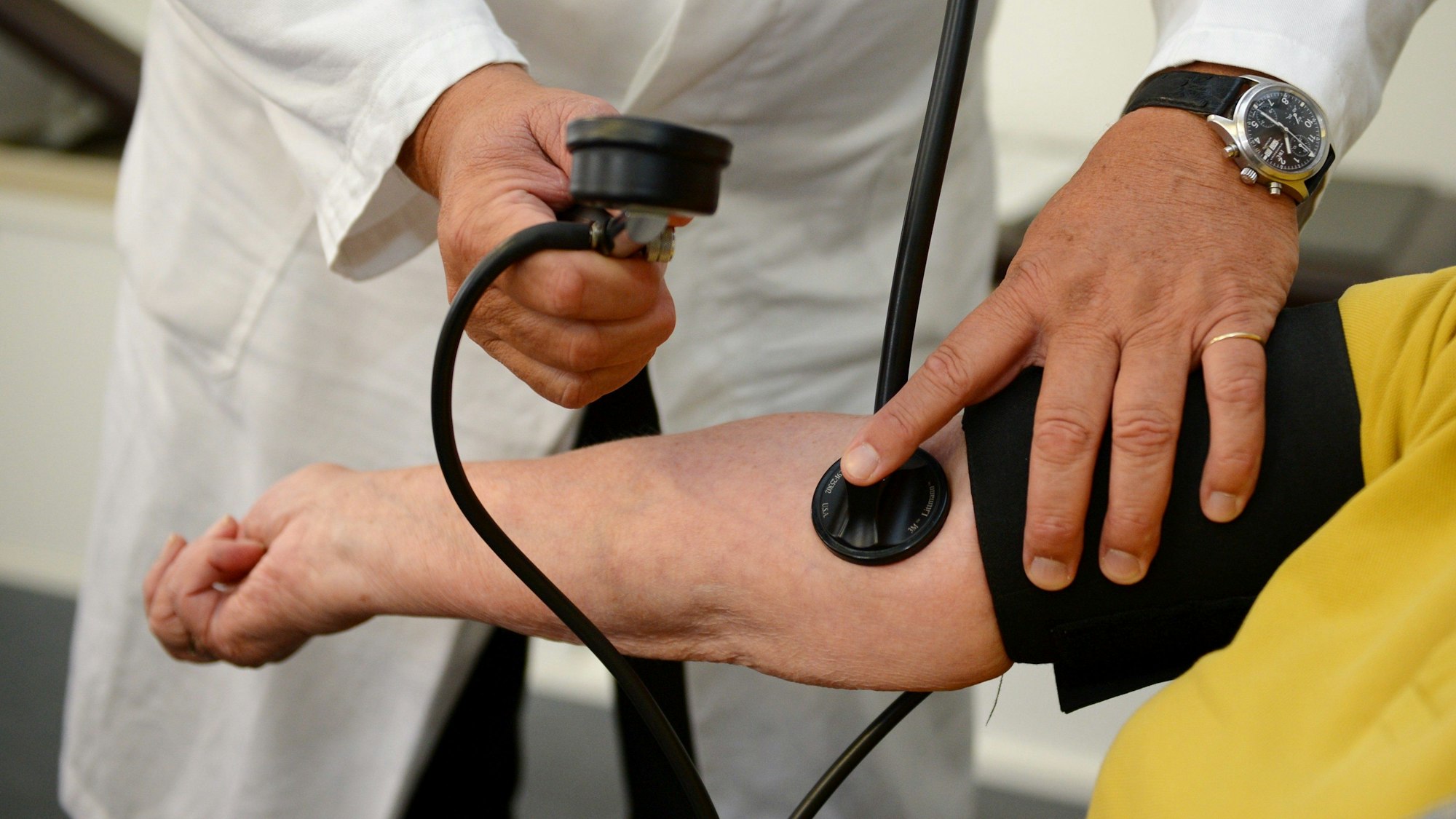 Ein Arzt misst bei einer Person den Blutdruck.