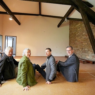 Joachim Starke, Roswitha Platzek, Thomas Kamm, Norbert Crump sitzen auf dem Boden im Obergeschoss der Begegnungsstätte in Nettersheim.