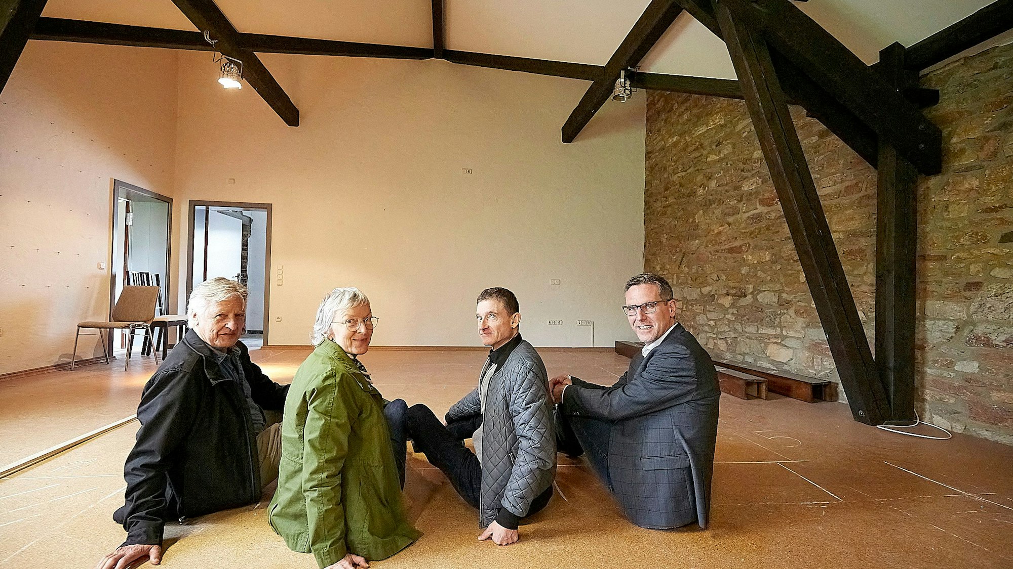 Joachim Starke, Roswitha Platzek, Thomas Kamm, Norbert Crump sitzen auf dem Boden im Obergeschoss der Begegnungsstätte in Nettersheim.