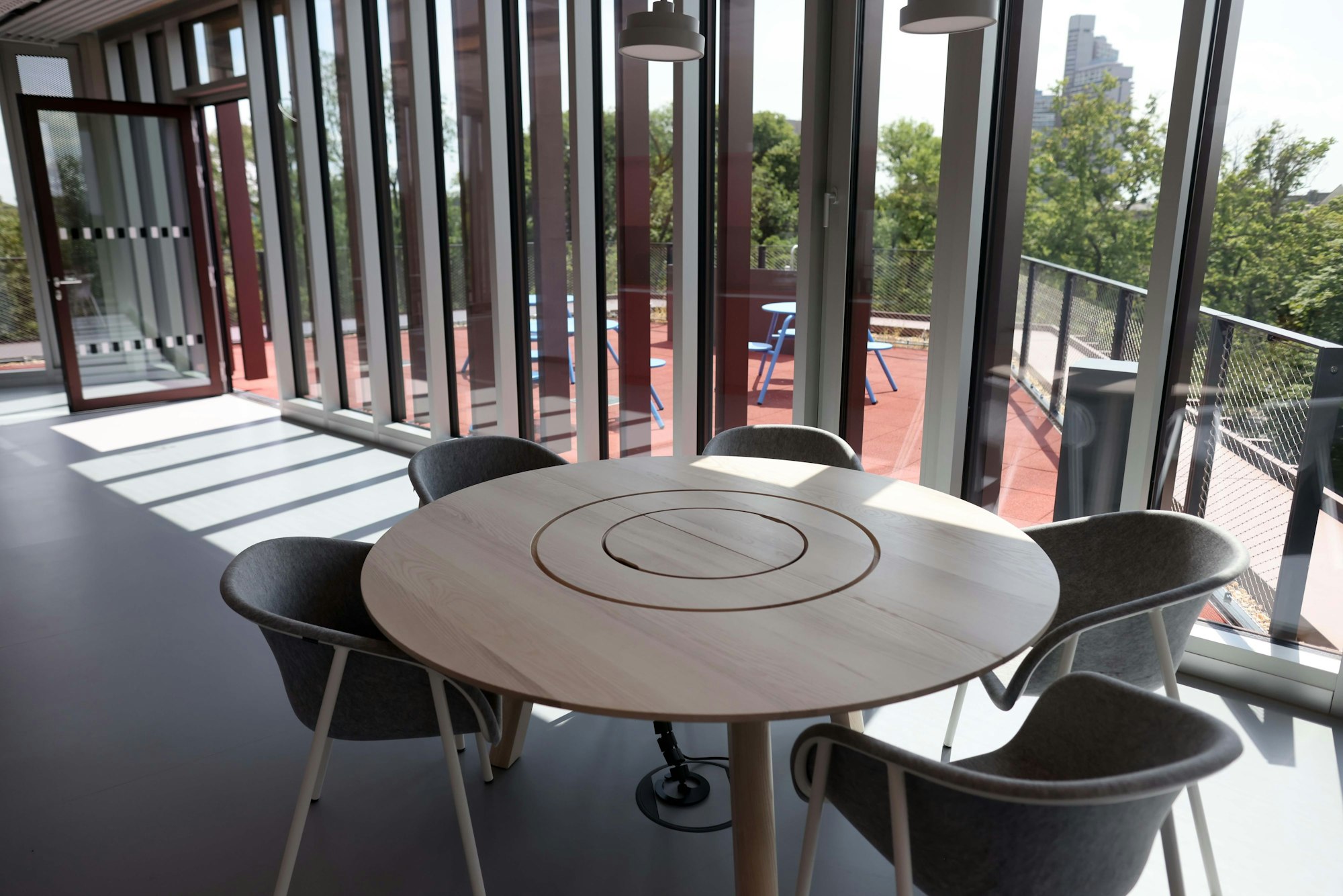 Zu sehen ist ein runder Tisch mit fünf Stühlen, einer der Konferenzzonen im Gebäude.