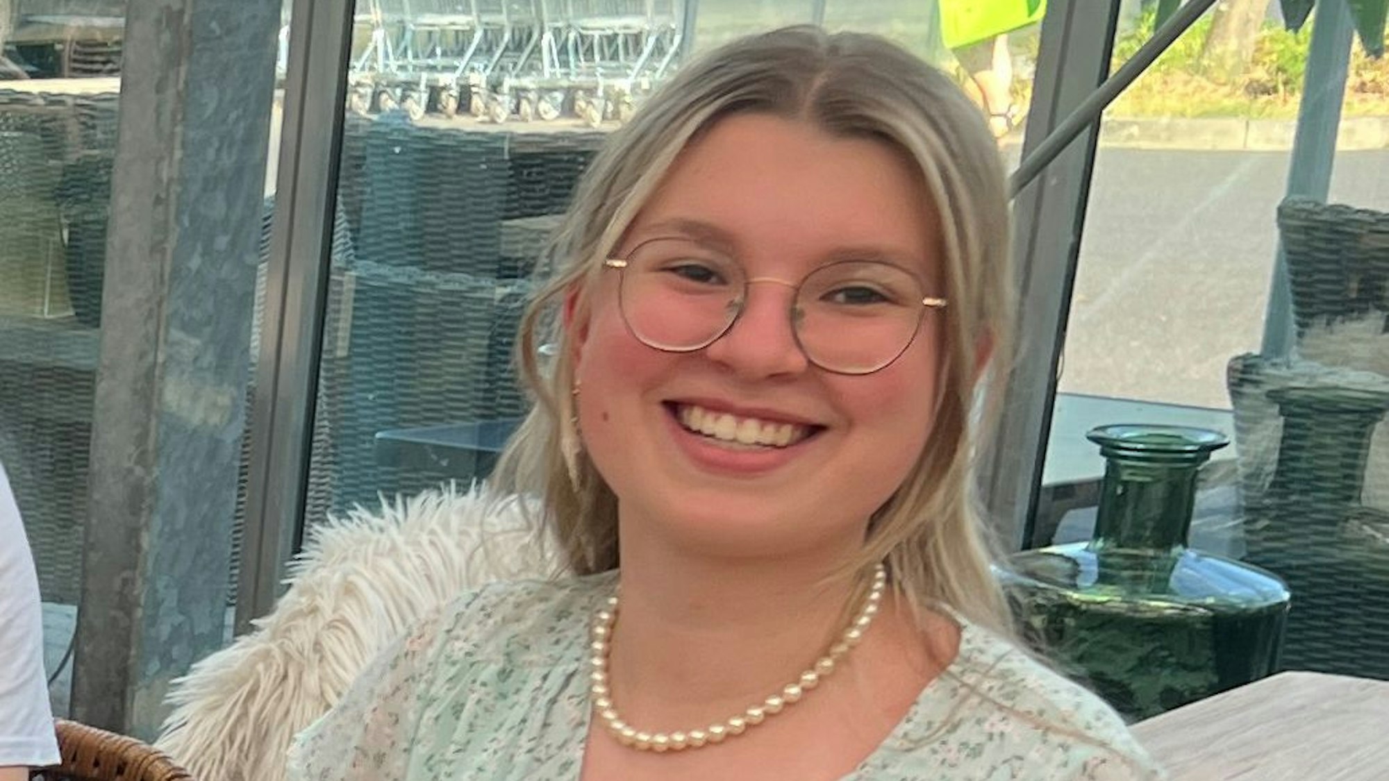Das Porträtbild zeigt Abiturientin Liv Grafe. Sie hat blondes Haar, trägt eine Brille, eine türkise Bluse und eine Perlenhalskette.