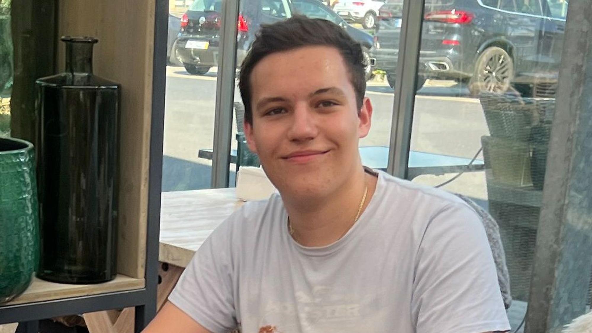 Das Porträtbild zeigt den Abiturienten Leon Tzikas. Er trägt ein weißes T-Shirt und hat kurze, braune Haare.