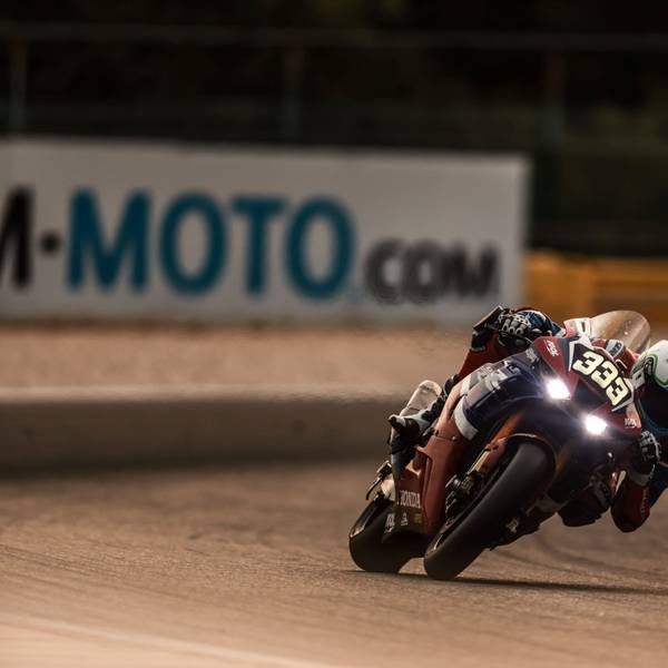 Im Bild ist ein Motorrad-Rennfahrer in der Dämmerung.