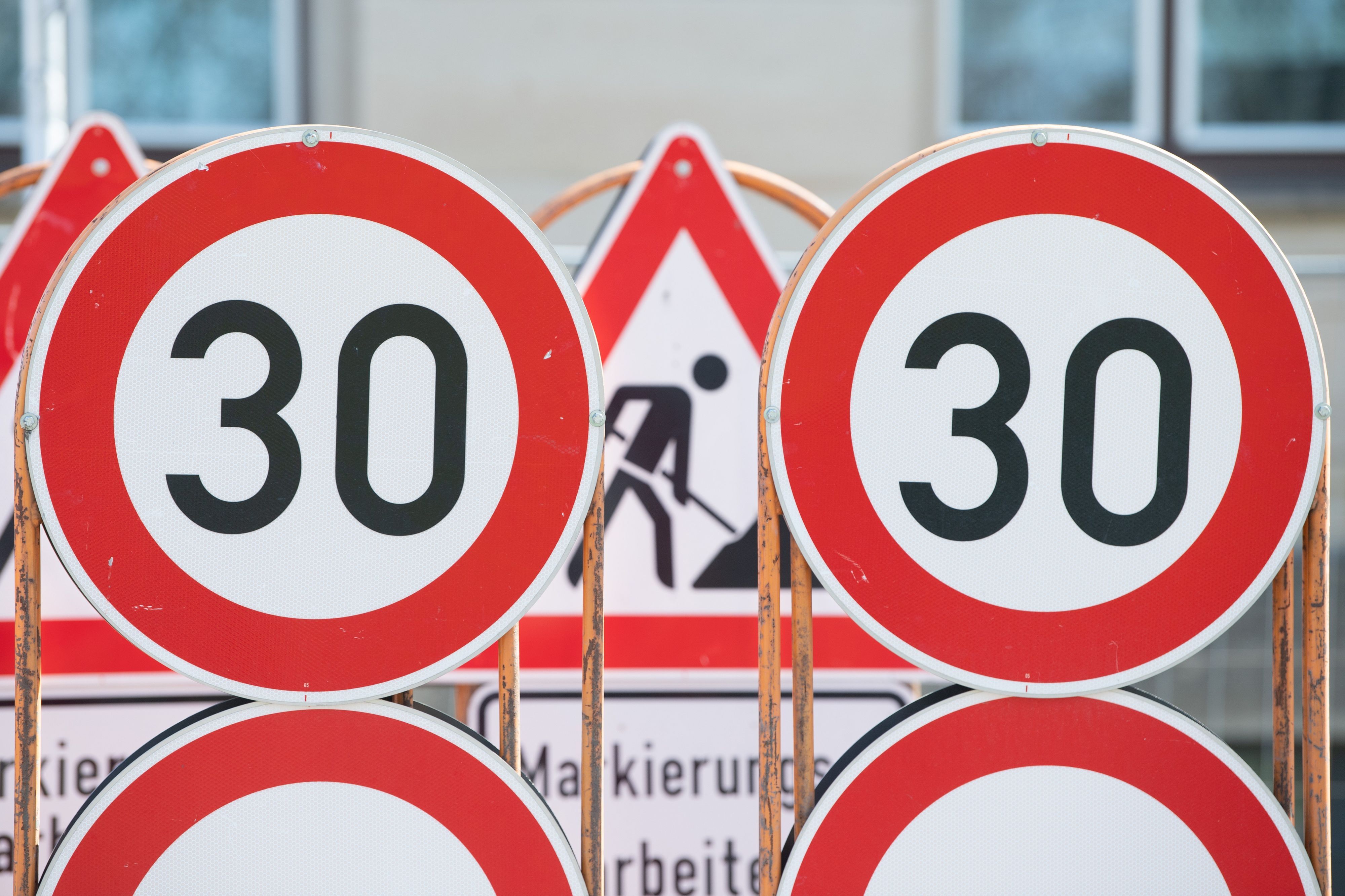 Verkehrsschilder für eine Baustelle und Tempo 30 Schilder stehen an einer Baustelle auf einem Anhänger.
