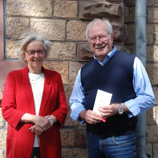 Das Bild zeigt einen Mann und eine Frau vor einer Bruchsteinwand.