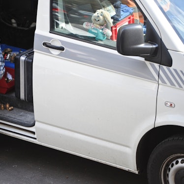 Ein Handwerker steht gebückt an seinem Auto. (Symbolfoto)