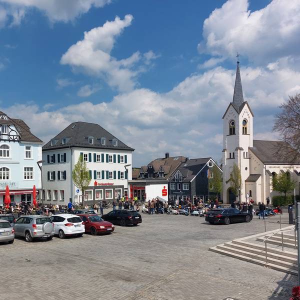 Blick auf den Platz. Einige Autos parken in der Mitte.