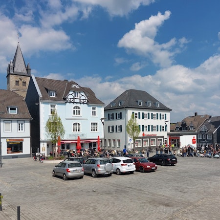 Blick auf den Platz. Einige Autos parken in der Mitte.