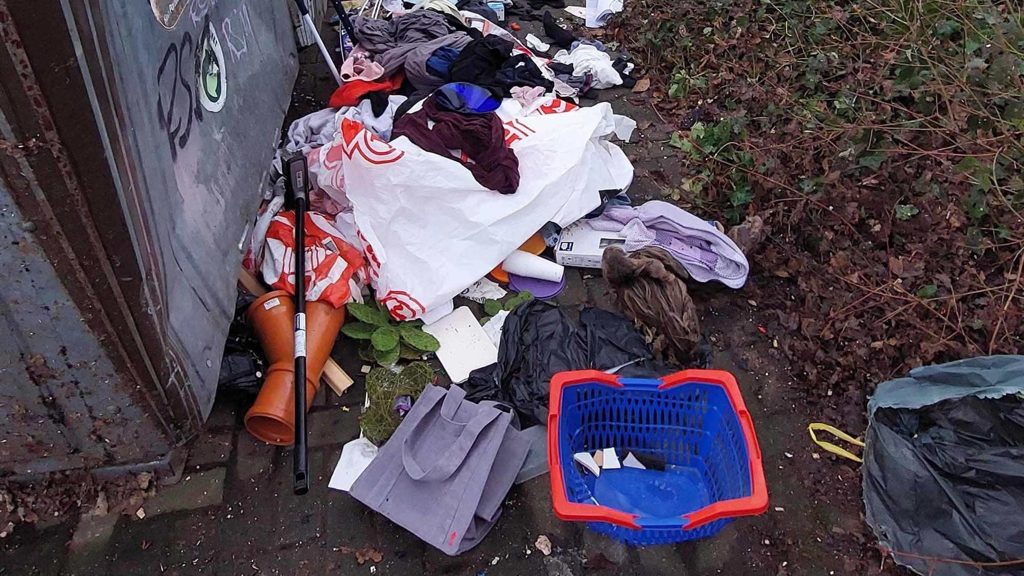 Allerlei Müll liegt vor einem Container auf der Erde.