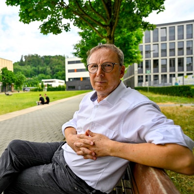 Ein Mann sitzt im Grünen auf einer Bank.