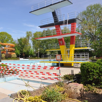 Auf dem Foto ist das Freibad Elsdorf mit Sprungturm und Rutsche zu sehen.