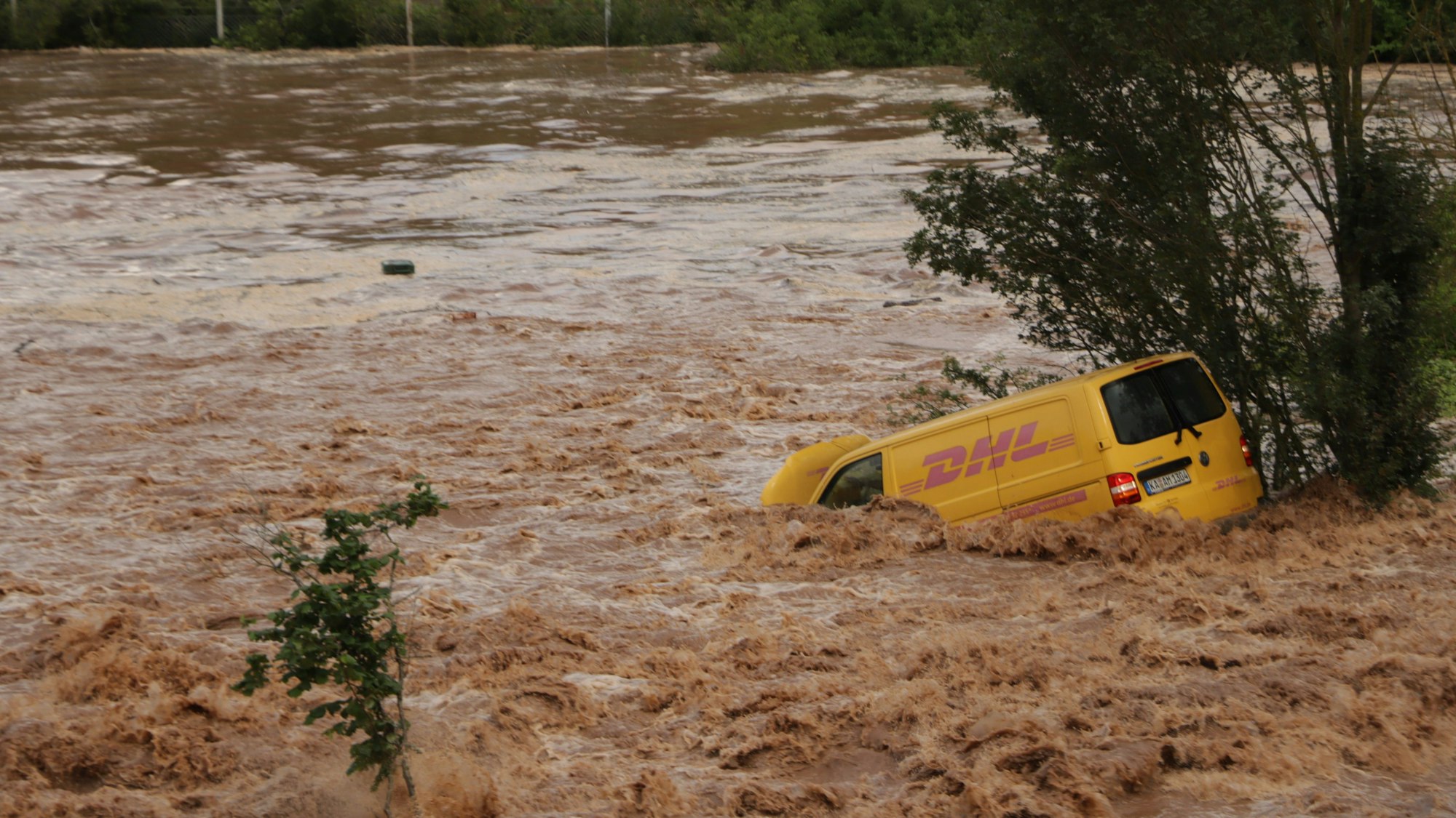 Auf dem Foto ist ein gelber DHL-Transporter zu sehen, der 2021 auf der Luxemburger Straße in den Wassermassen versank.