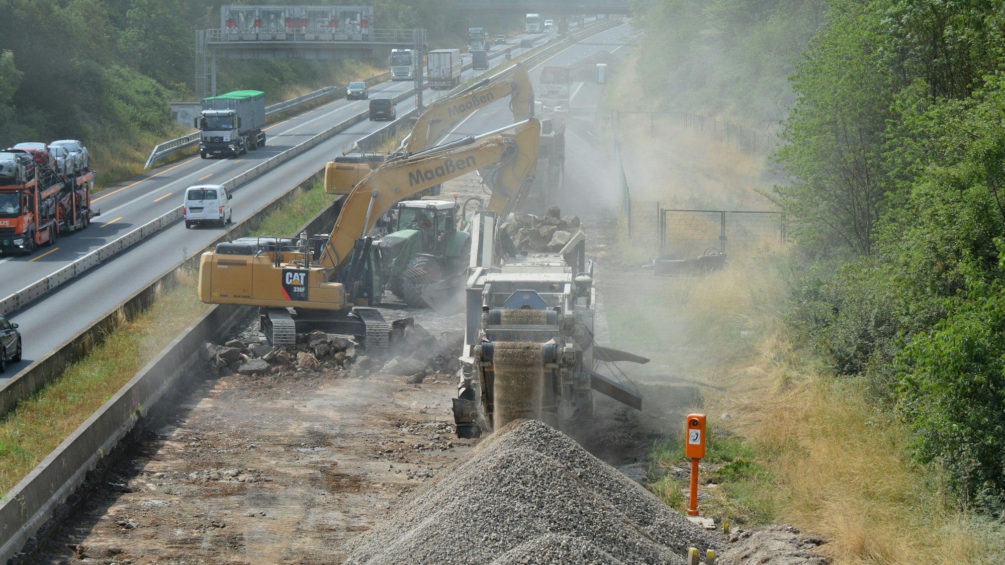 Auf dem Foto ist die Baustelle auf der A 61bei Kerpen zu sehen. Es stehen nur wenige Fahrstreifen zur Verfügung. Daneben brechen Baumaschinen den Belag auf.