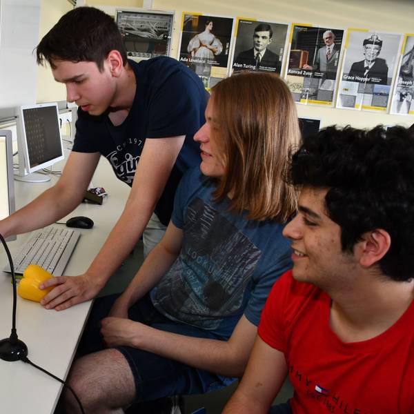 Das Foto zeigt drei Schüler und Obst vor einem Computer.