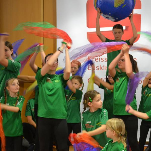 Kinder schwenken Tücher im S-Forum der Kreissparkasse.