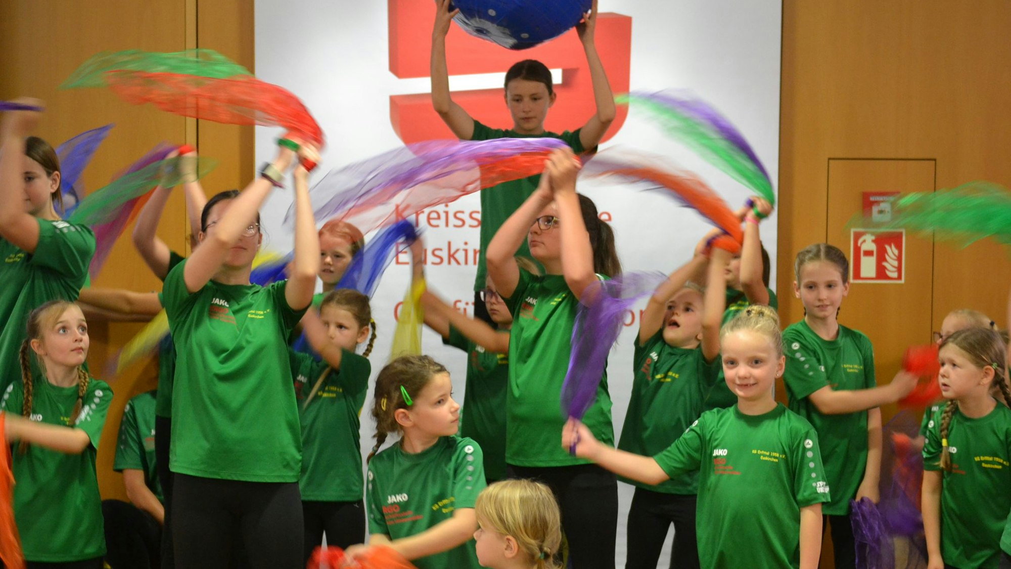 Kinder schwenken Tücher im S-Forum der Kreissparkasse.