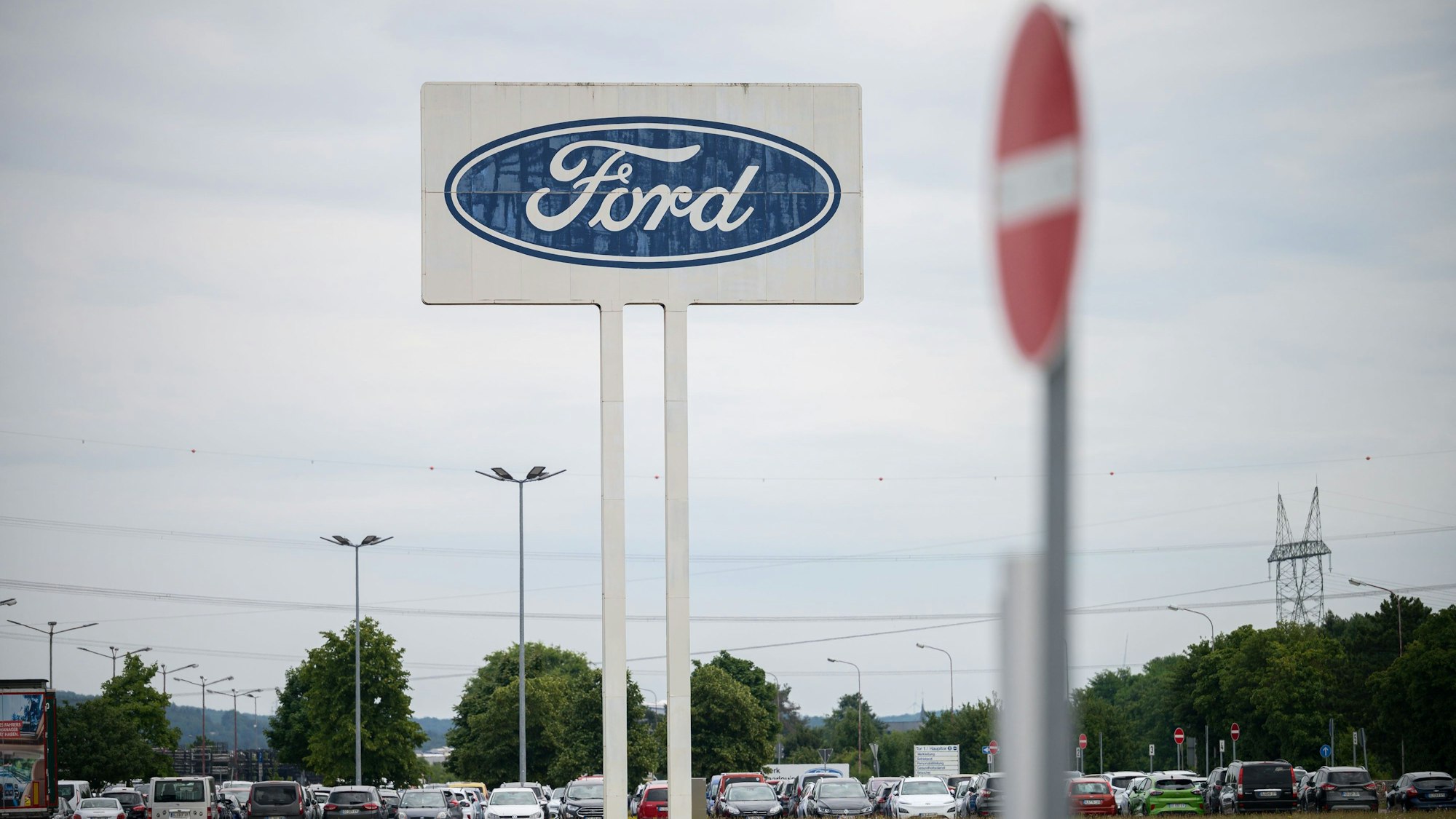 Saarlouis: Das große Logo von Ford, das auf dem Parkplatz des Werks Saarlouis steht, mit einem Durchfahrt Verboten Schild davor.