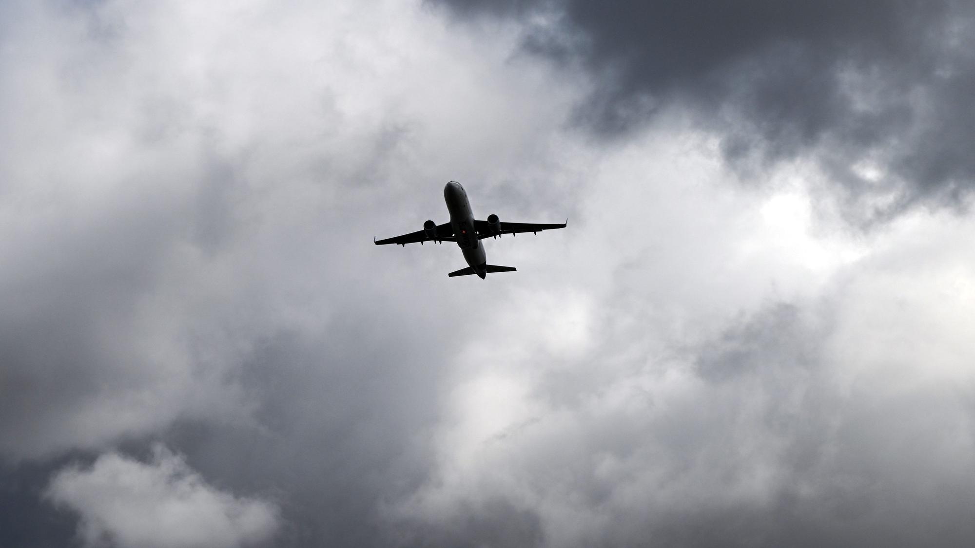 Über einem Flugzeug, das vom Flughafern Düsseldorf startet, türmen sich dunkle Wolken. (Archivbild)