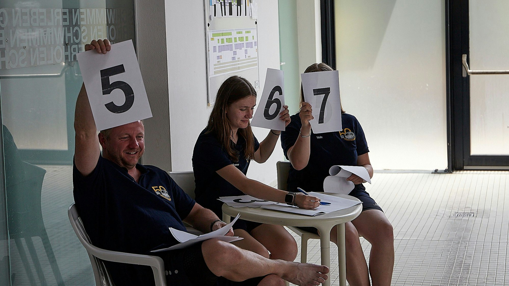 Mitglieder der DLRG halten Bewertungstafeln in die Höhe.