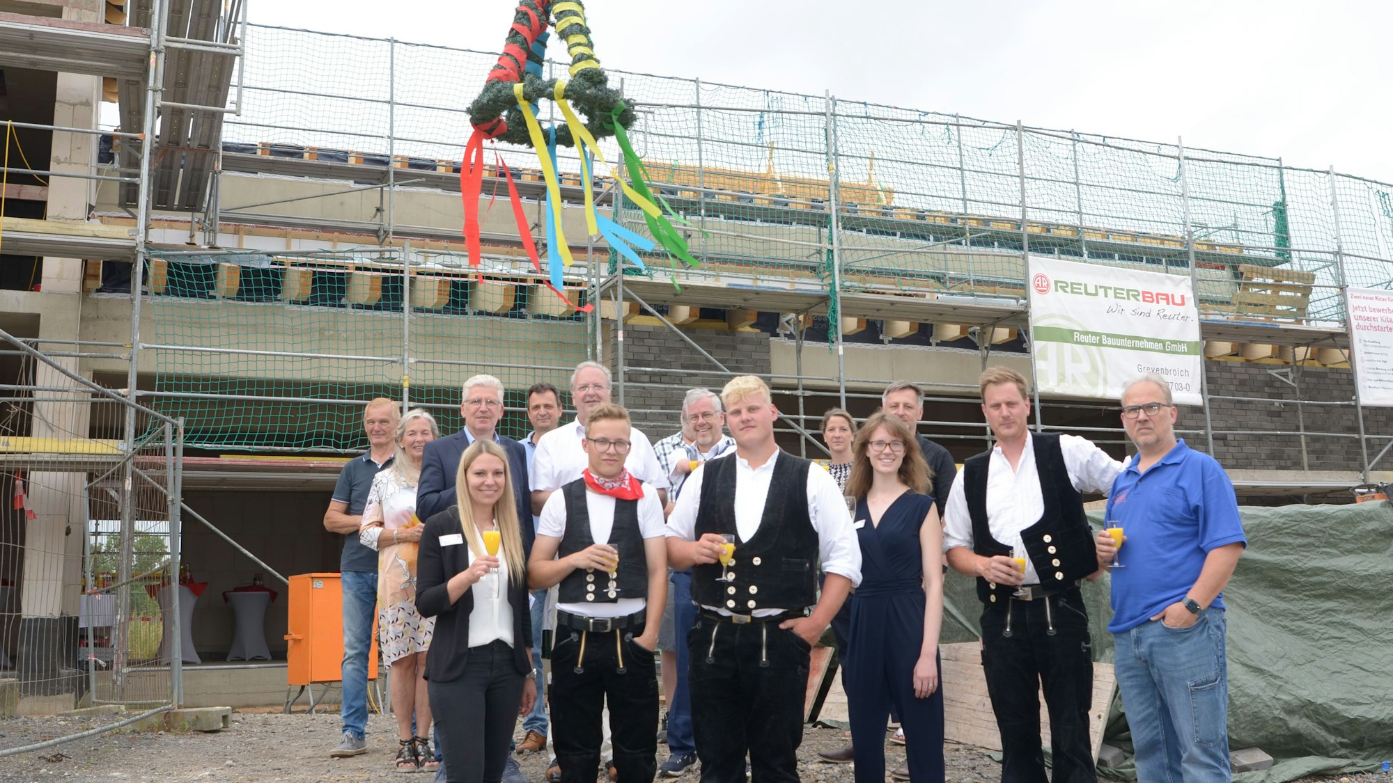 Vertreter von Stadt, Diakonie und weitere am Bau Beteiligte stehen unter dem Richtkranz.