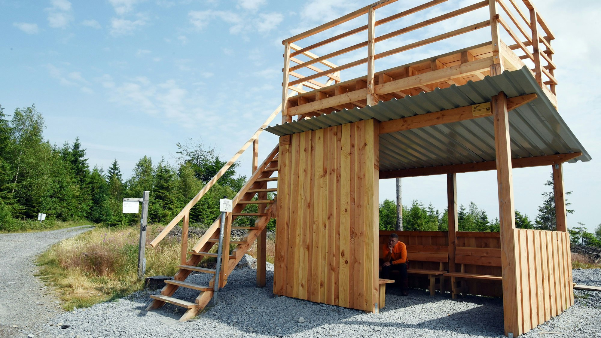 Das Bild zeigt eine Holzhütte, deren Flachdach über eine Treppe bestiegen werden kann.