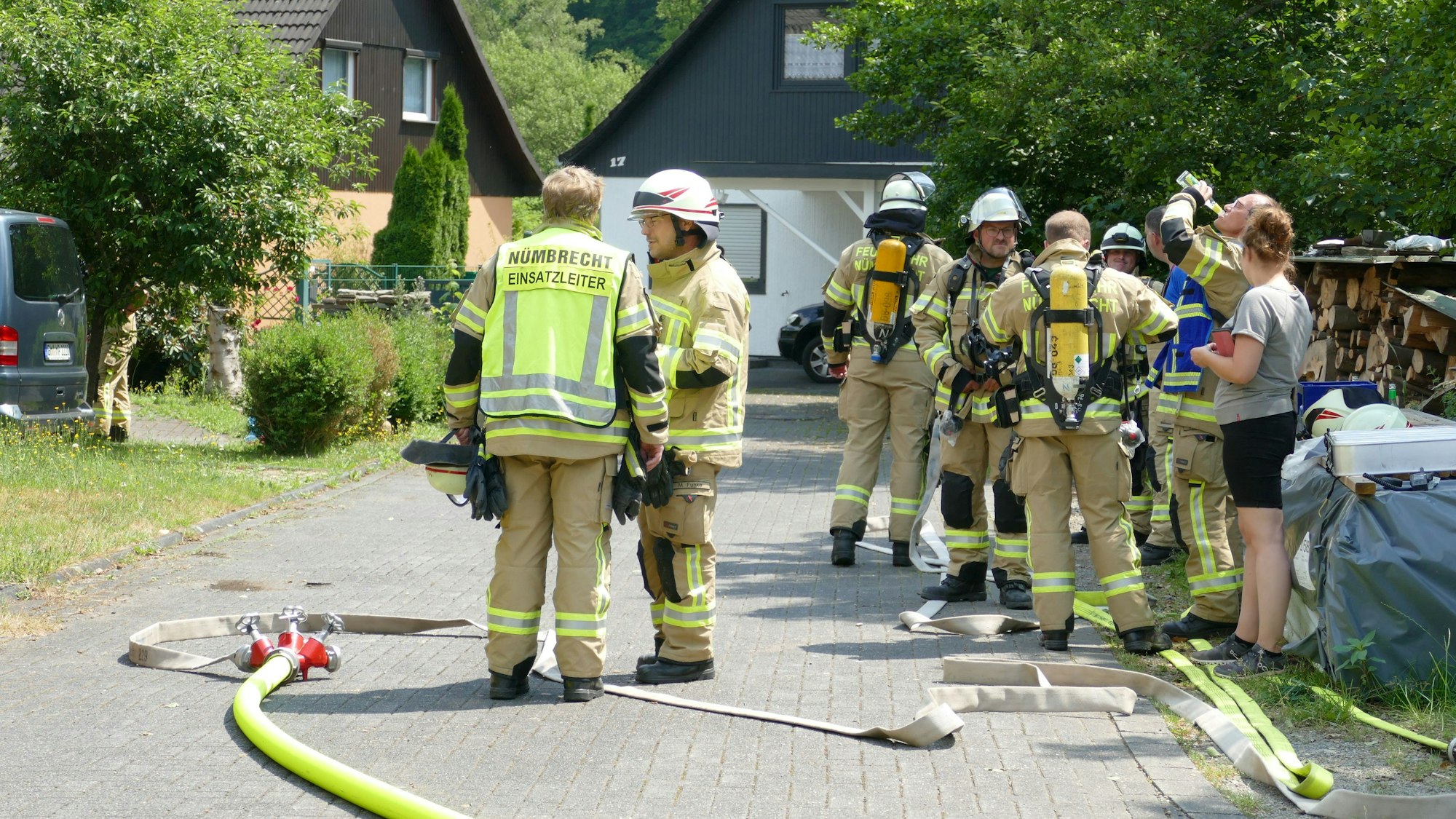 Feuerwehrleute stehen vor dem Haus, vor dem ein Gastank steht.