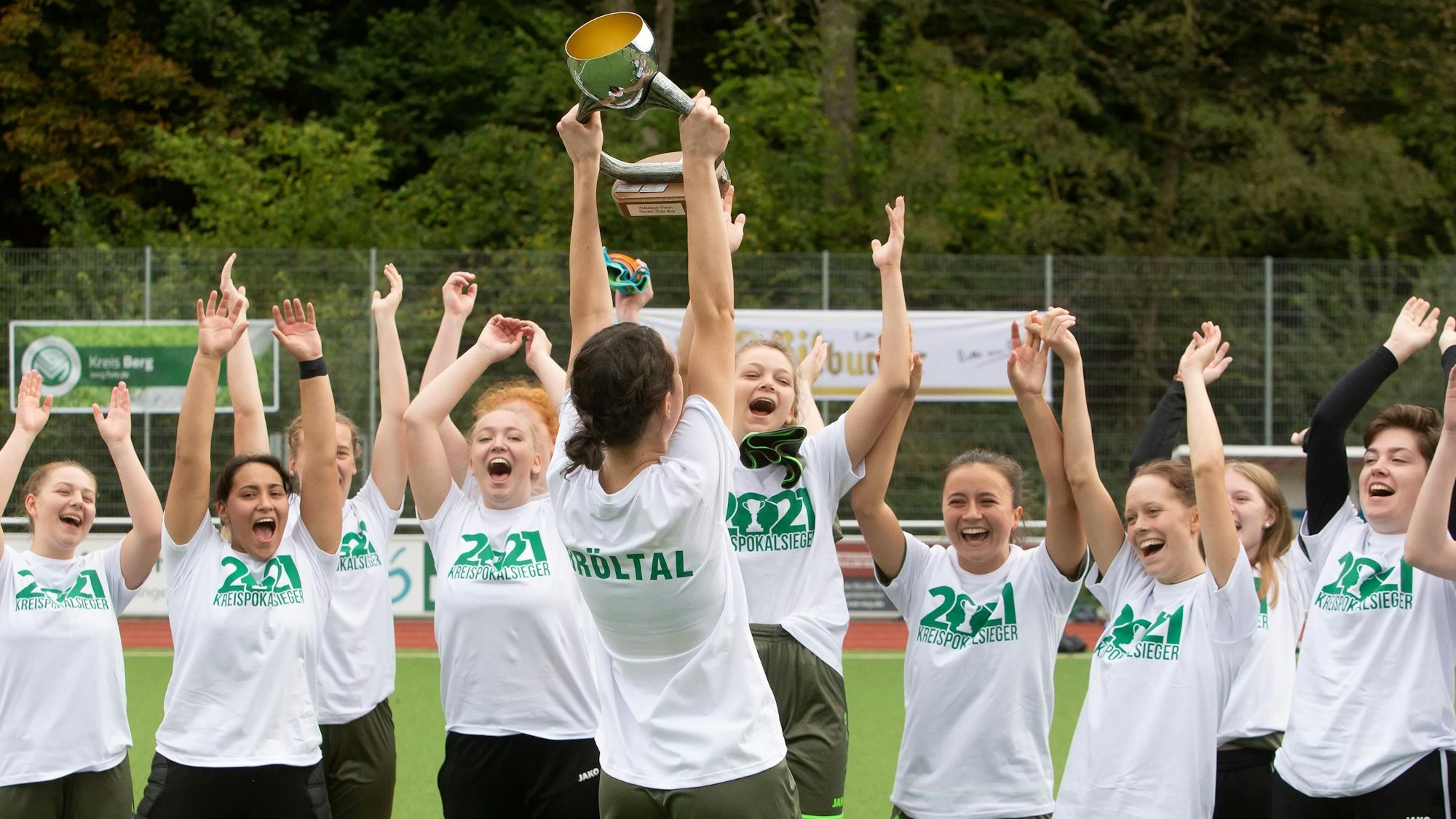 Jubelnde Fußballerinnen recken einen Pokal in die Höhe.