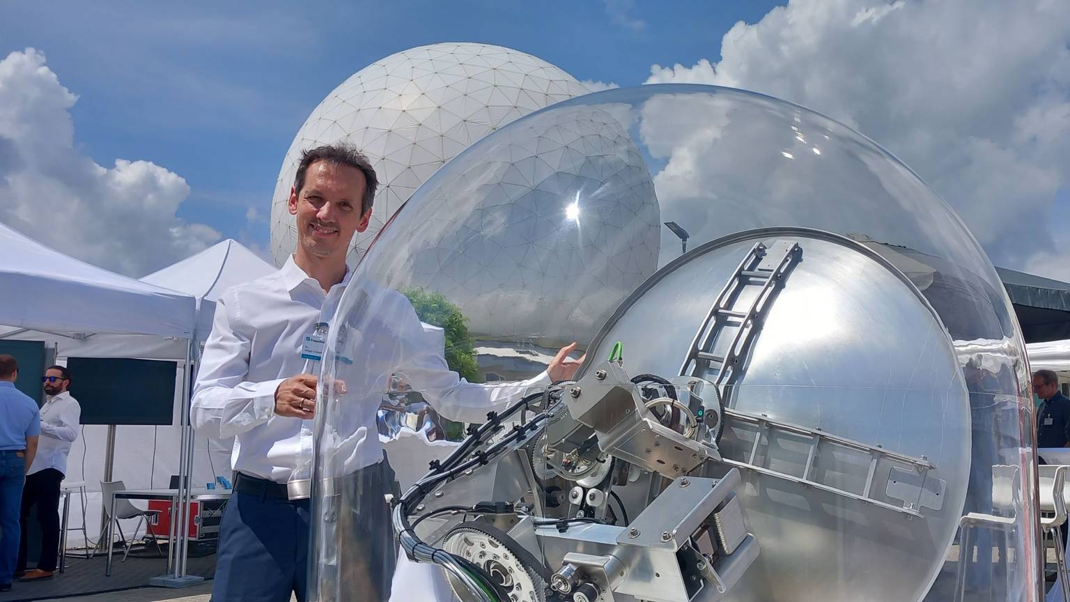 Diego Cristallini zeigt das Satelliten basierte Passivradar beim Wachtberg-Forum von Fraunhofer. Im Hintergrund das Radom in Wachtberg-Werthhoven.