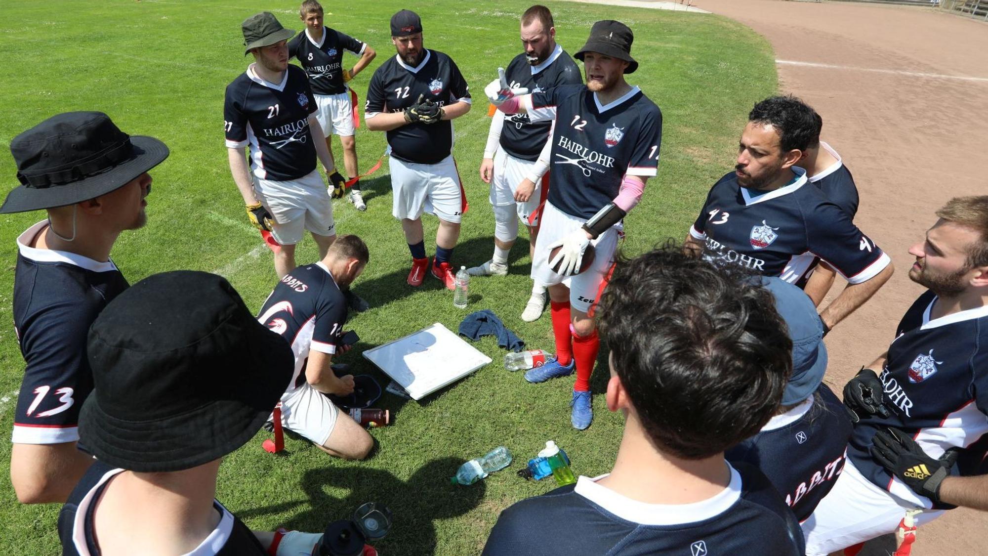 Spieler der Mannschaft stehen am Spielfeldrand zusammen und besprechen die Spielstrategie.