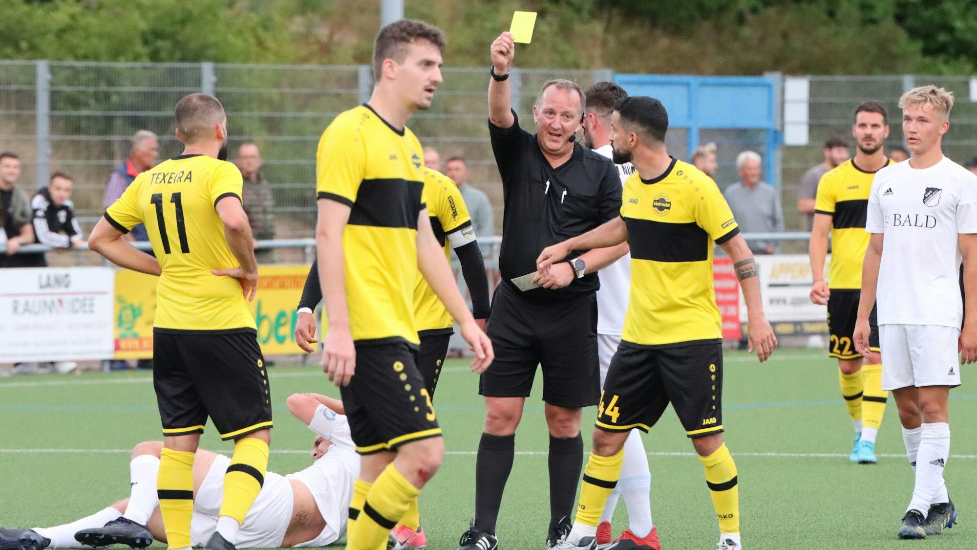 Ein Schiedsrichter zeigt einem Fußballspieler die Gelbe Karte.
