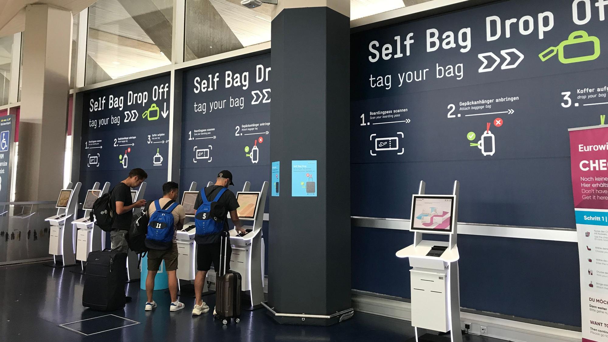 Drei Reisende geben am Self Bag Drop Off des Flughafens Köln/Bonn selbst ihr Gepäck ab.