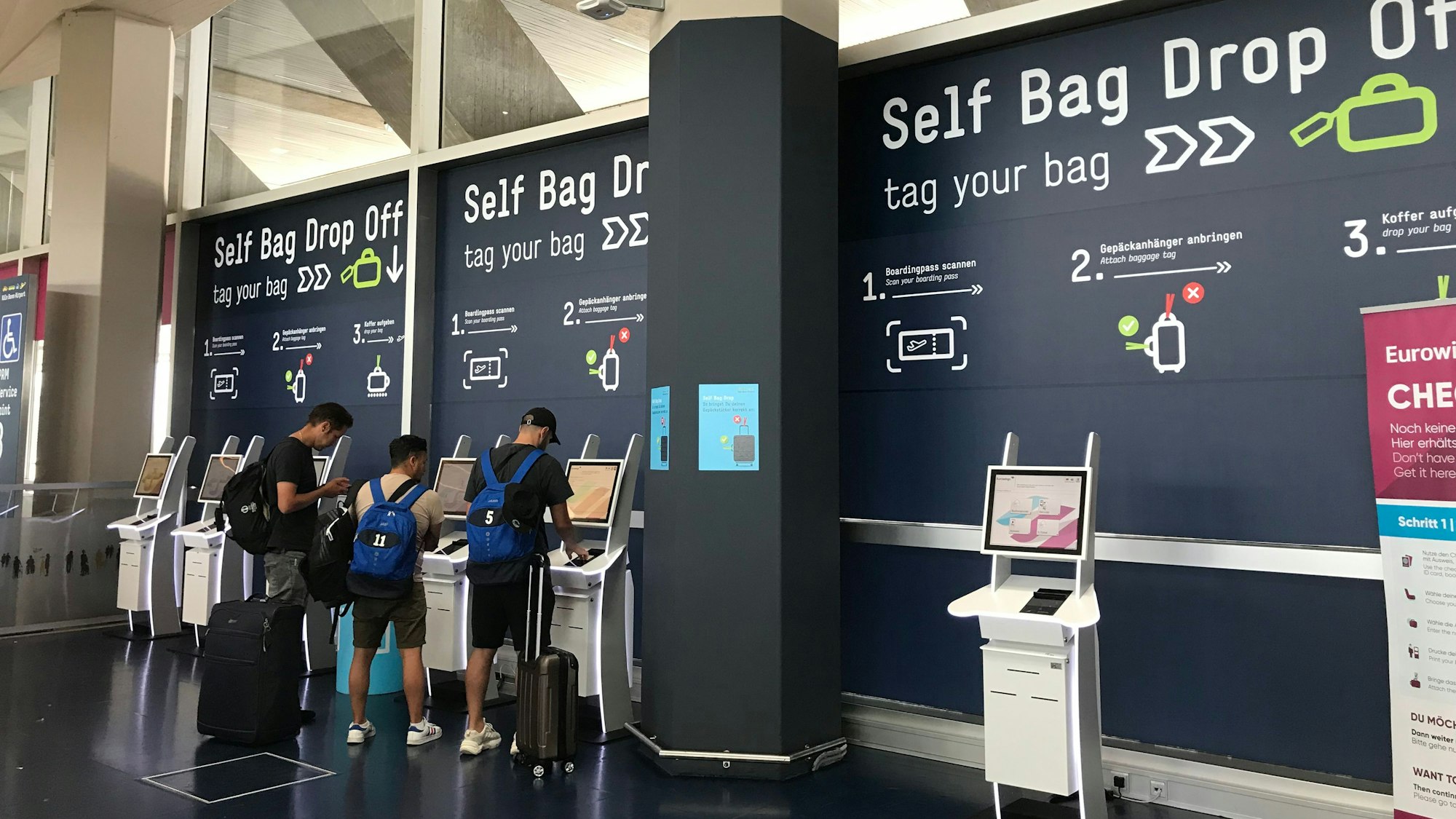 Drei Reisende geben am Self Bag Drop Off des Flughafens Köln/Bonn selbst ihr Gepäck ab.