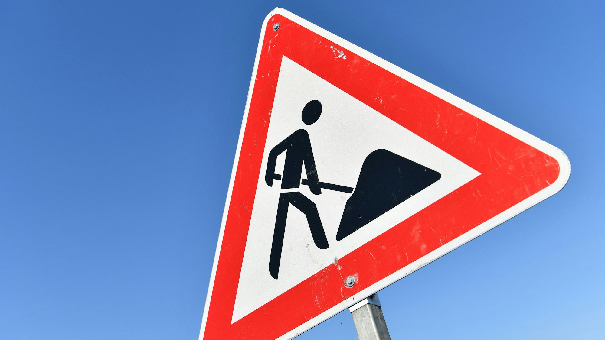 Das Foto zeigt das Verkehrszeichen „Achtung Baustelle“ vor blauem Himmel.