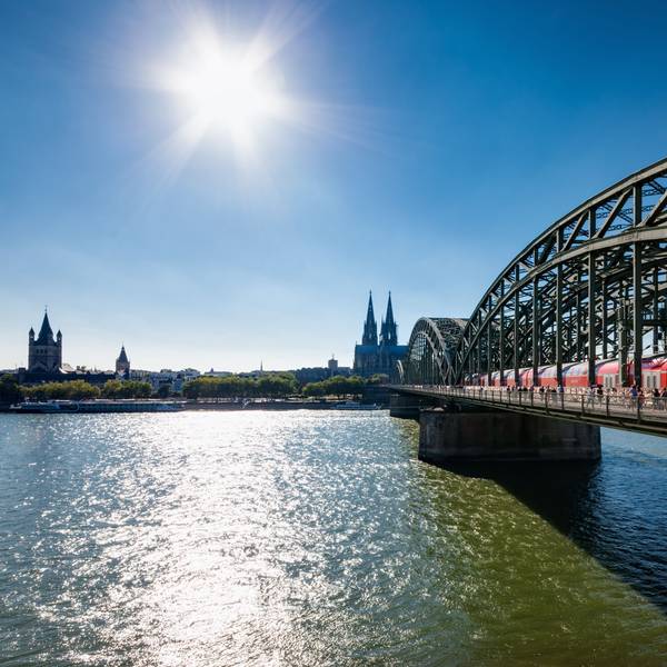 Blick auf die von der Sonne angestrahlte Hohenzollernbrücke über den Rhein, im Hintergrund der Kölner Dom