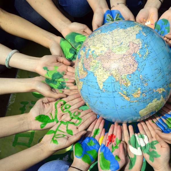 Studenten halten einen Globus in ihren bemalten Händen.