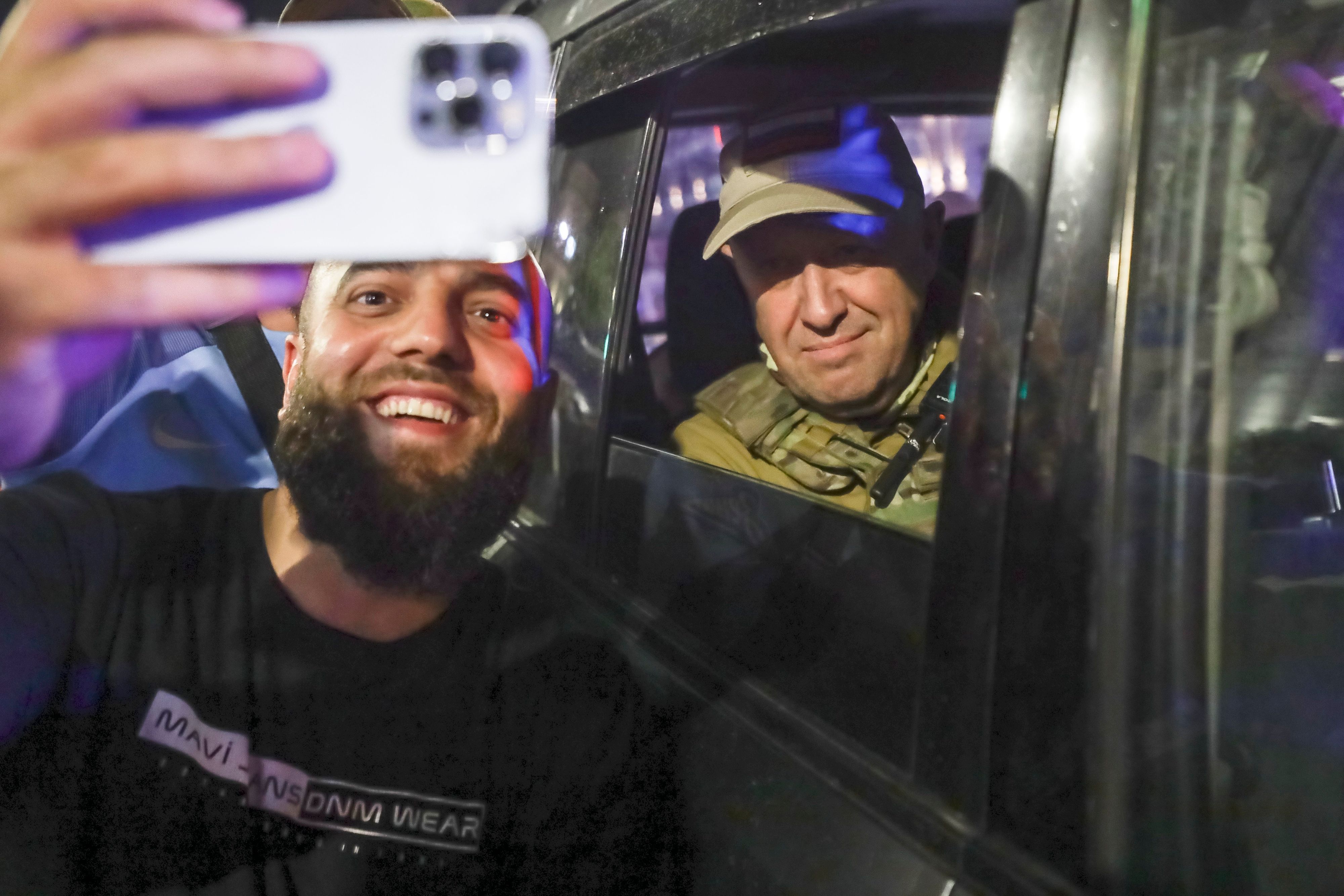 dpatopbilder - 24.06.2023, Russland, Rostow am Don: Jewgeni Prigoschin (r), Eigentümer des Militärunternehmens Wagner Group, sitzt in einem Militärfahrzeug und macht ein Selfie mit einem Zivilisten auf einer Straße in Rostow am Don, Russland, bevor er einen Bereich des Hauptquartiers des südlichen Militärbezirks verlässt. Kreml-Sprecher Dmitri Peskow sagte, dass Prigoschins Truppen, die sich ihm beim Aufstand angeschlossen haben, nicht strafrechtlich verfolgt werden und dass denjenigen, die sich nicht angeschlossen haben, vom Verteidigungsministerium Verträge angeboten werden. Nach der Einigung am Samstag befahl Prigoschin seinen Truppen, ihren Marsch auf Moskau abzubrechen und sich in Feldlager in der Ukraine zurückzuziehen, wo sie an der Seite russischer Truppen kämpften. Foto: -/AP/dpa +++ dpa-Bildfunk +++