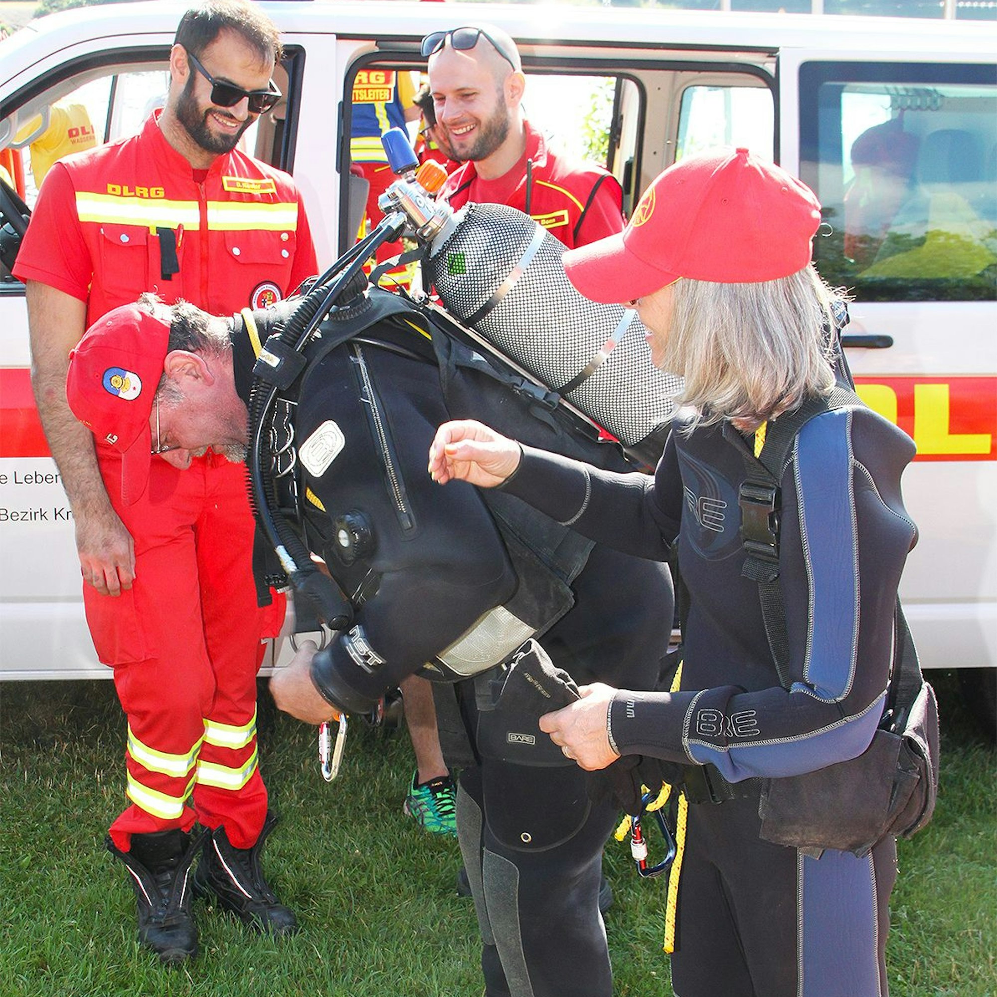 Der DLRG-Taucher legt seine Ausrüstung an, seine Kameraden assistieren.