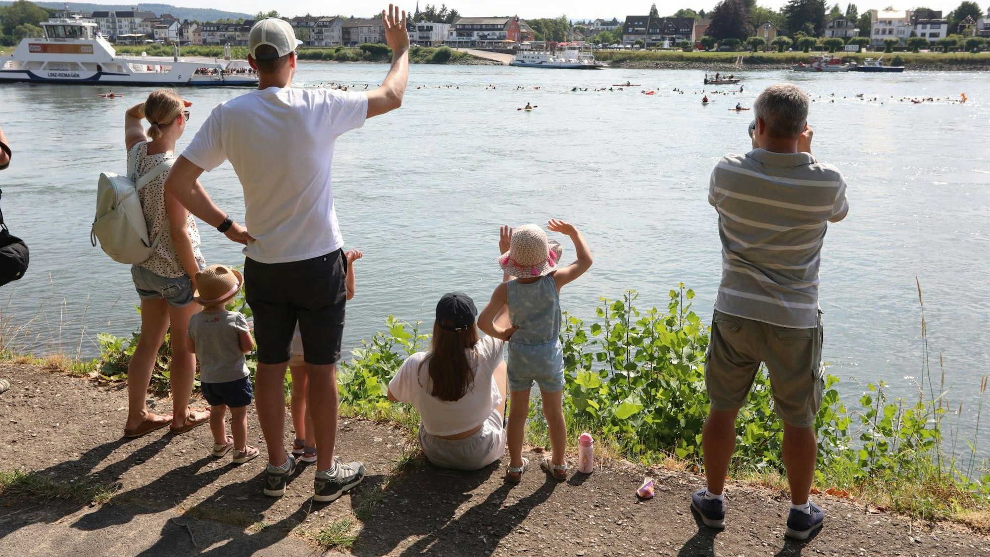 Zuschauer winken den Schwimmern vom Ufer aus zu.