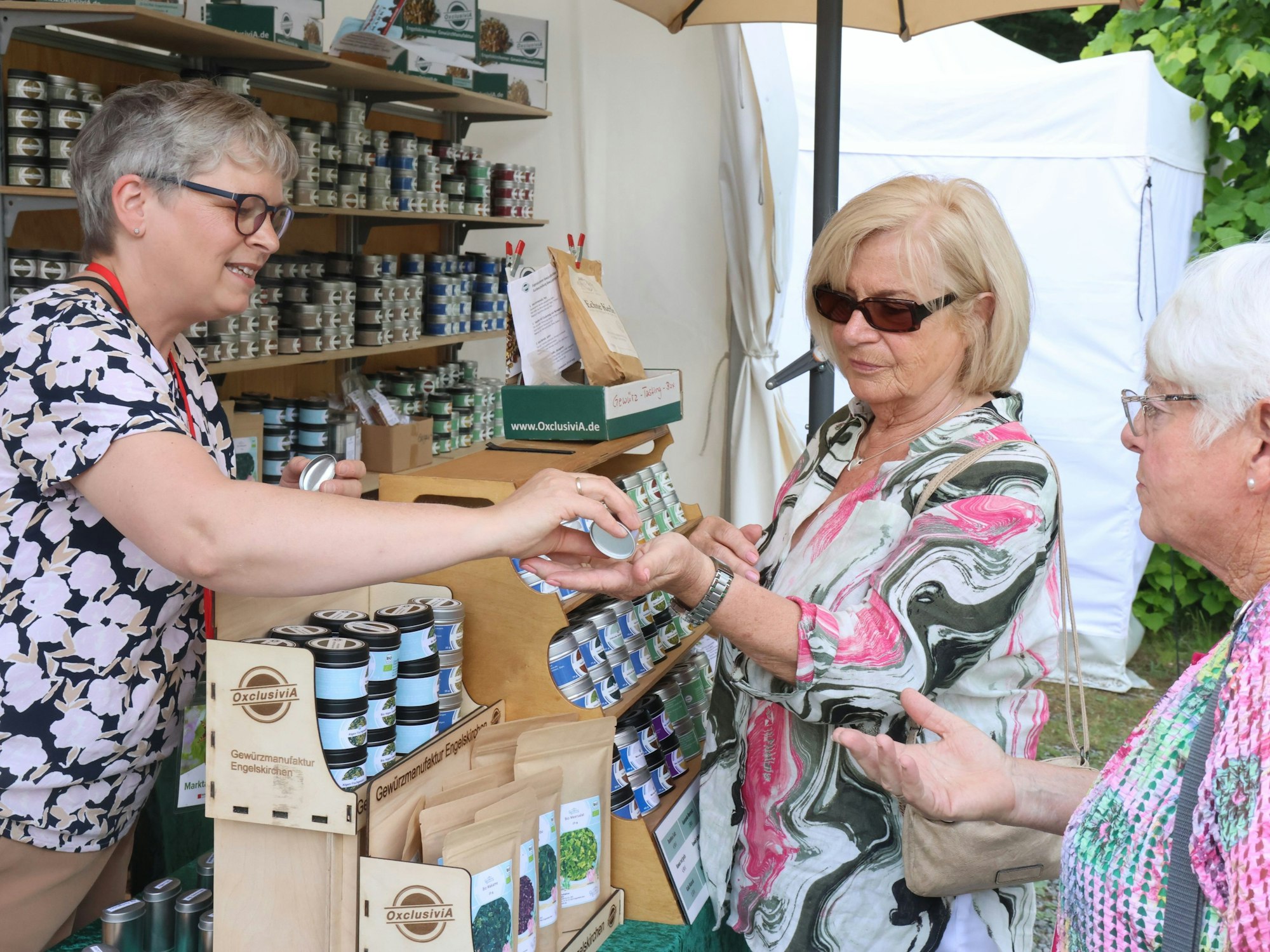 Eine Frau überreicht zwei anderen kostenlose Gewürzproben.