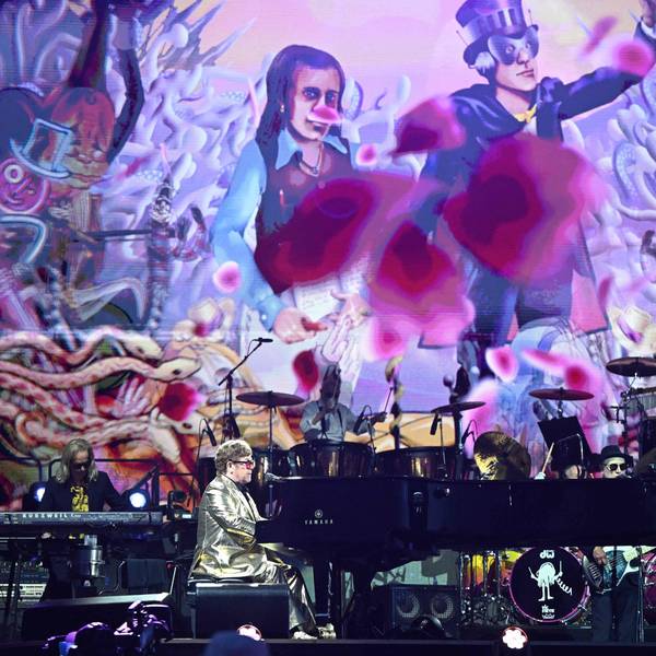 Elton John bei seiner Bühnenshow auf dem Glastonbury-Festival. Die Bühne ist bunt und farbenfroh.