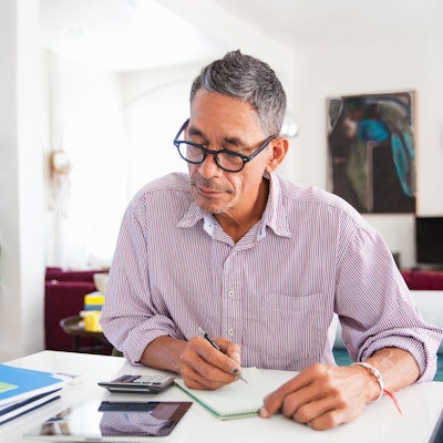 Ein Mann mit Brille arbeitet zu Hause an seinen persönlichen Finanzen.