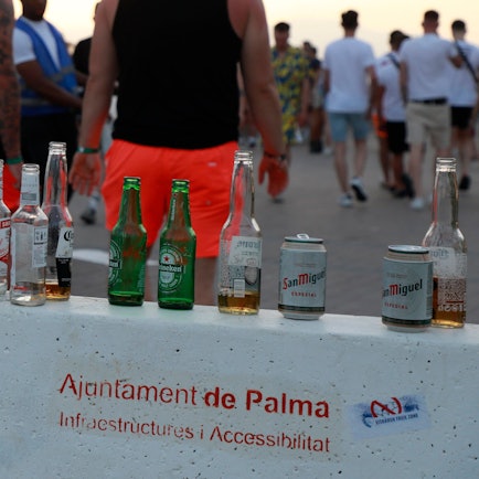 Menschen haben sich am Abend an der Promenade am Strand von Arenal versammelt. Auf einer Mauer stehen mehrere leere Flachen alkoholischer Getränke. Auf der Urlaubsinsel Mallorca gibt es immer wieder Klagen über Betrunkene, die grölend herumtorkeln, in Ecken pinkeln, sich übergeben oder ihre Notdurft öffentlich erledigen.