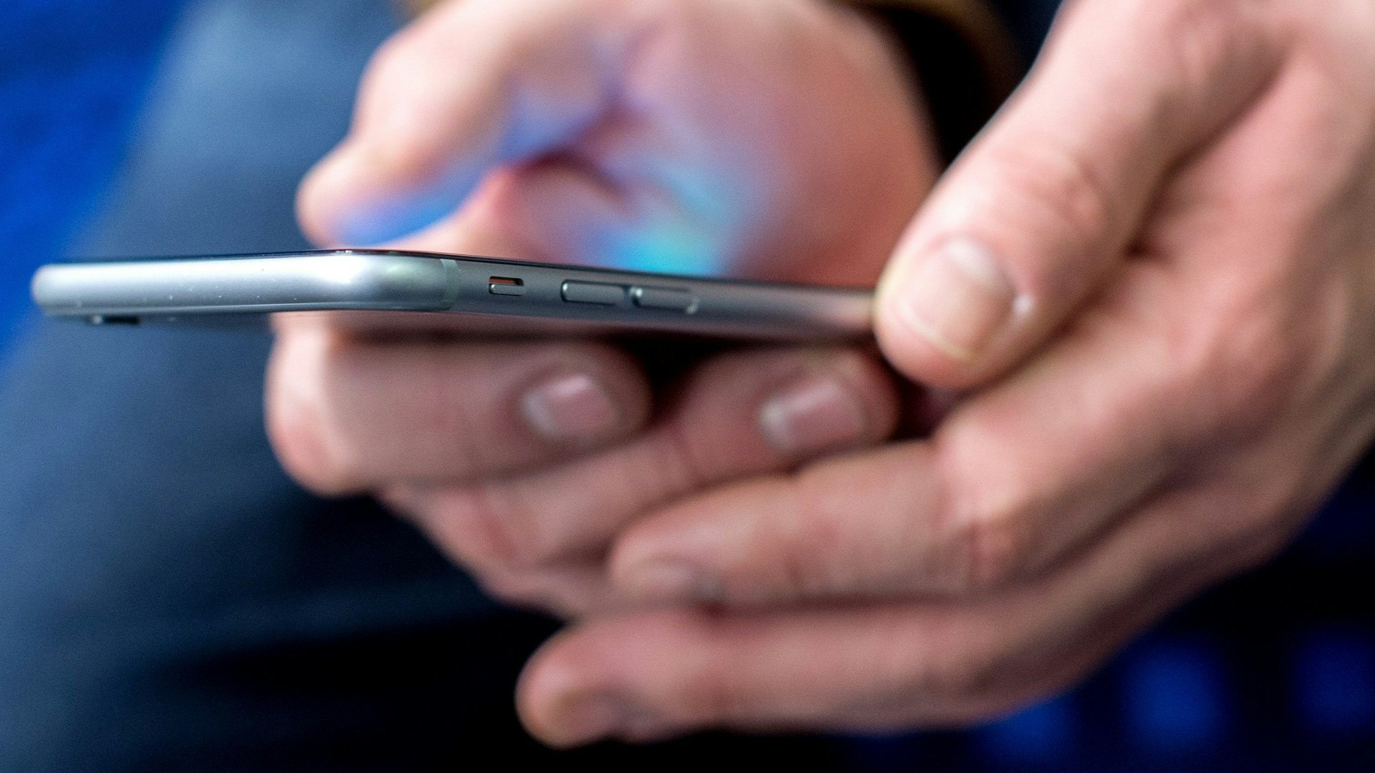 Mann hält Smartphone in den Händen.