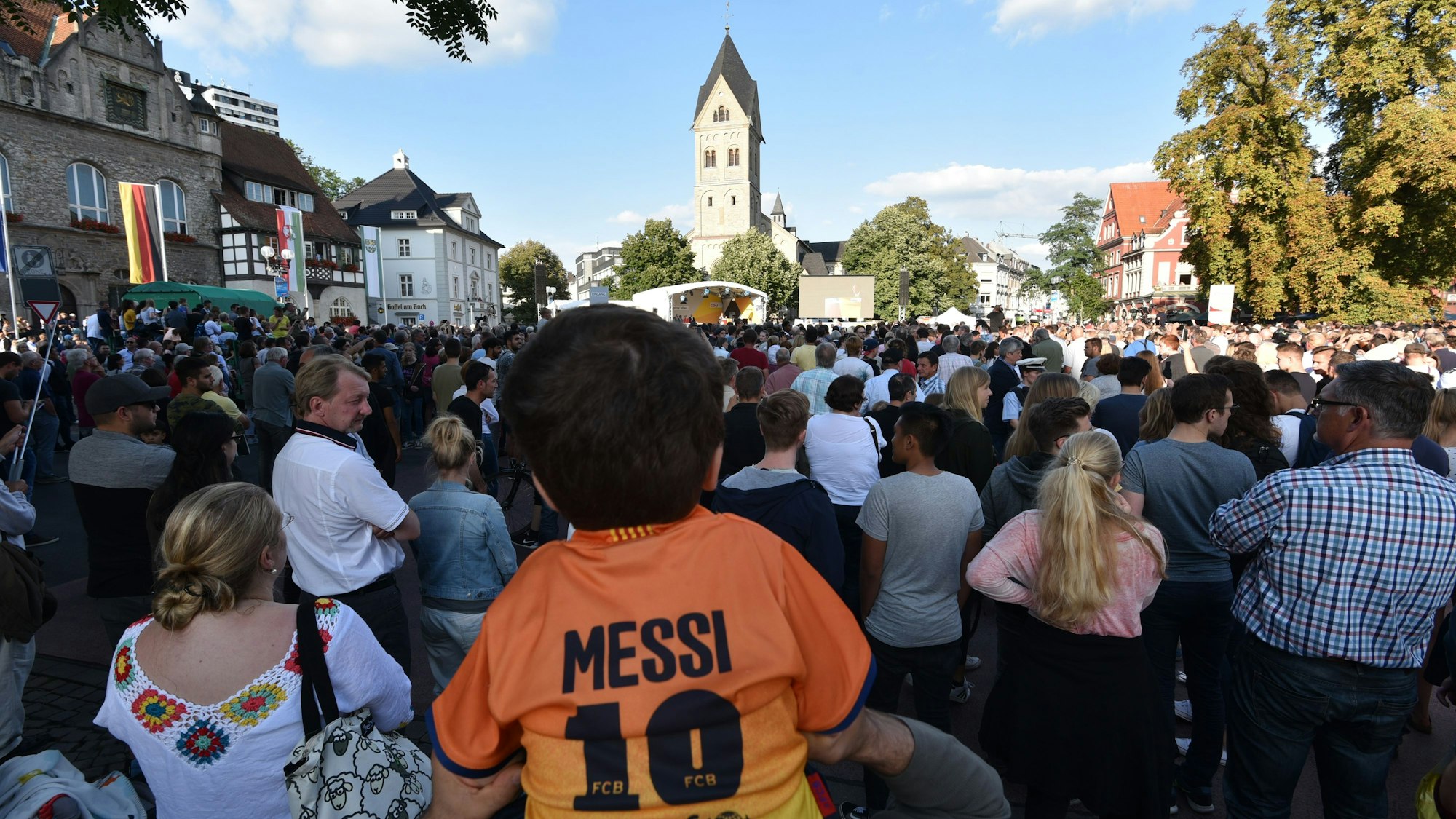 In einer Menschenmasse in Odenthal sitzt ein J`Kind auf den Schultern seines Vaters.