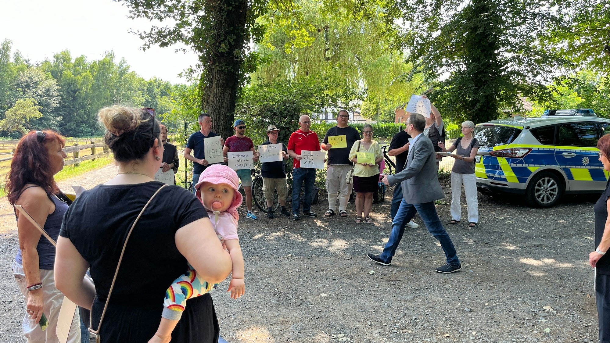 Mehrere Leute mit Schildern stehen auf einer Lichtung.