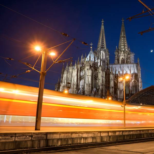 Ein Zug fährt im Dunkeln am Kölner Dom vorbei.