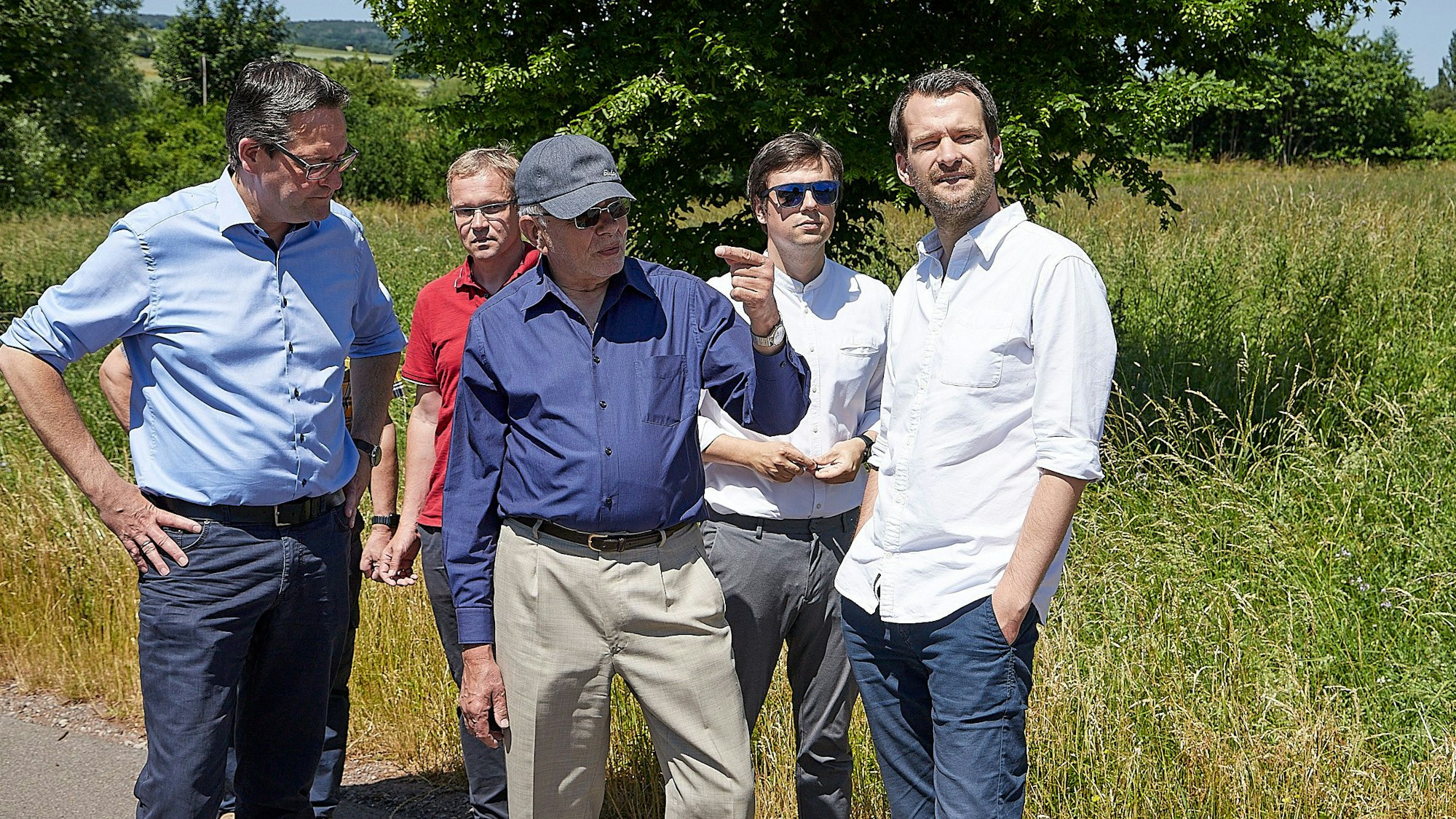 Die Besuchergruppe und der Schevener Ortsvorsteher in einem Bereich am Ortsrand von Scheven.