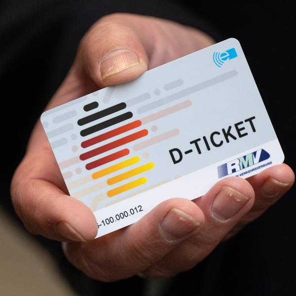 Zu sehen ist eine Hand, die ein Deutschlandticket in die Kamera hält.